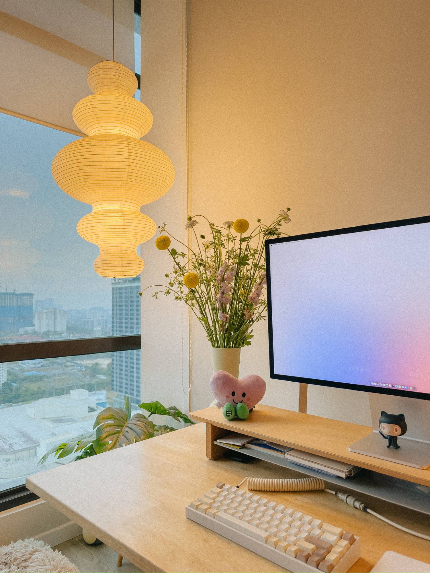 Desk by the window with a paper lantern and fresh flowers